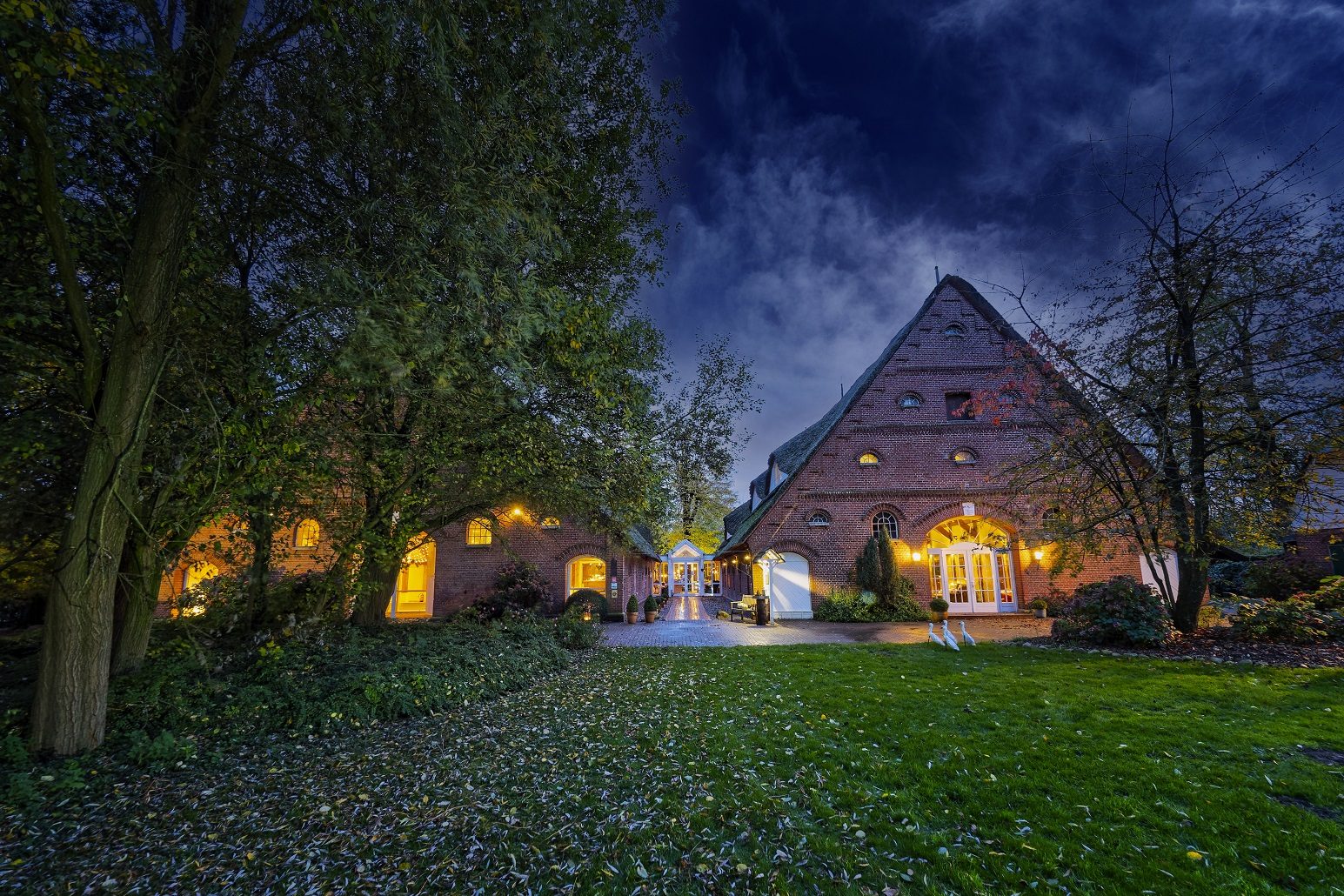 Gut Schöneworth at dusk, the thatched estate lit from within