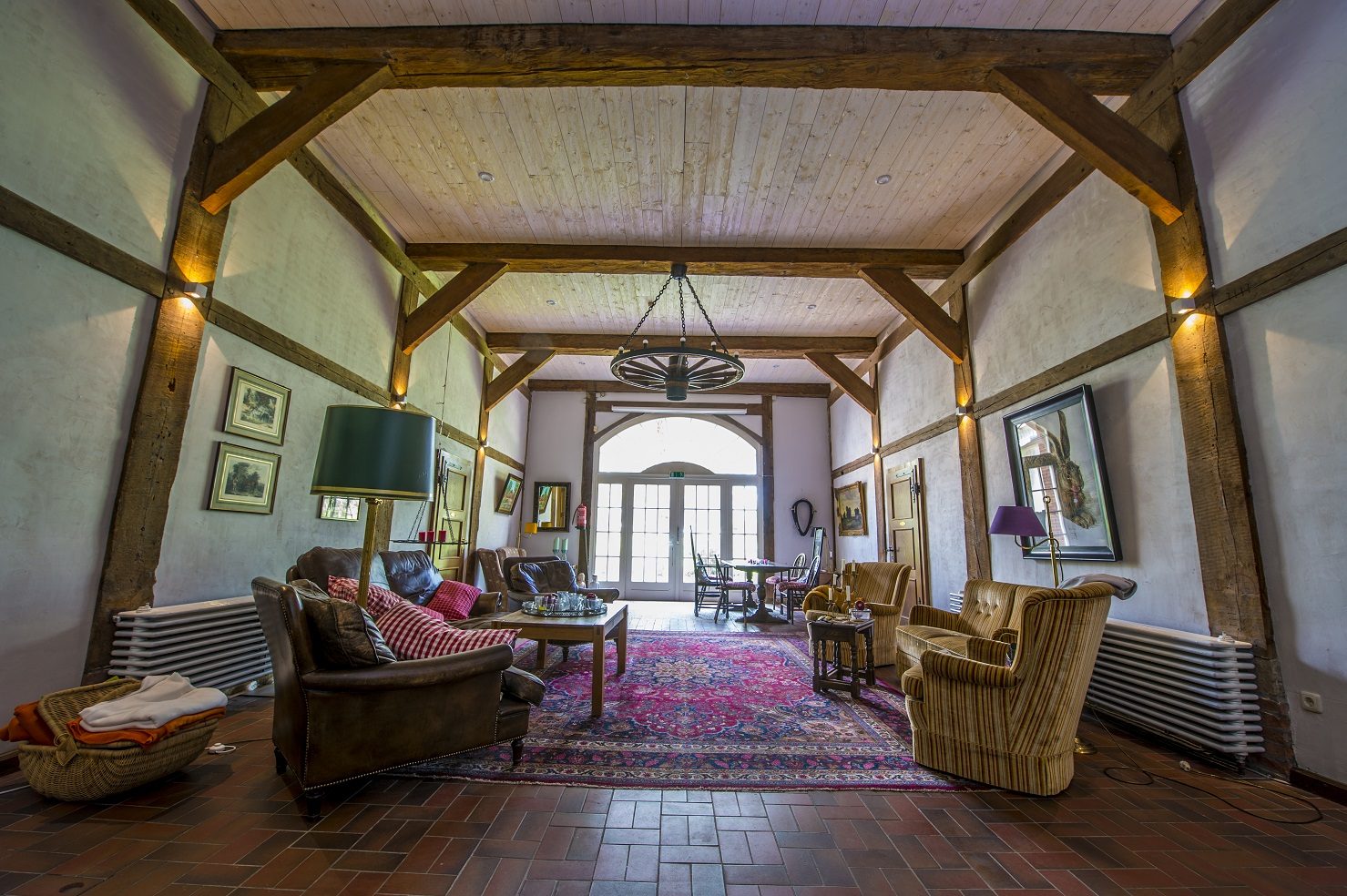 A beamed lounge with sofas, armchairs, rugs and a chandelier